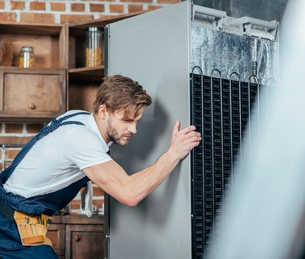 young-repairman-in-protective-workwear-moving-refr-resize